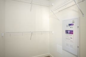 A white wall with a white door and a white shelf.