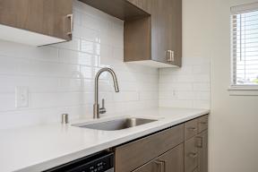 A kitchen with a white counter top and a stainless steel sink.