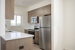 A modern kitchen with a stainless steel refrigerator and wooden cabinets.