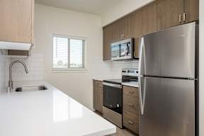 A modern kitchen with a stainless steel refrigerator and white countertops.
