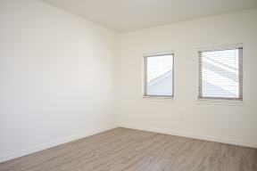 A room with two windows and wooden flooring.