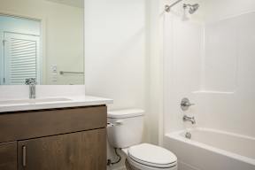 A white toilet sits next to a white bathtub in a bathroom.