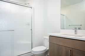 A white bathroom with a toilet, sink, and shower.