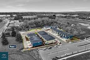 A black and white photo of a housing development with the text "Phase 1" on the bottom left.
