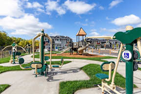 A playground with a green and yellow slide and a play structure with a wheelchair symbol.