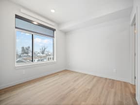 an empty living room with a large window and wood floors