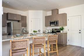 A kitchen with a refrigerator, microwave, oven, and sink.