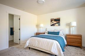 A bedroom with a bed, nightstand, and lamp.