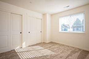 A room with a carpeted floor and a window with blinds.