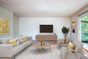 A living room with a grey couch, a wooden coffee table, and a television.