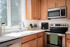 A kitchen with wooden cabinets and a black microwave above the stove.