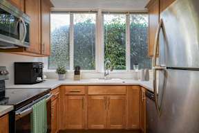 A kitchen with wooden cabinets and a stainless steel refrigerator.