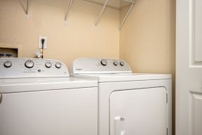 Two white washing machines in a laundry room.