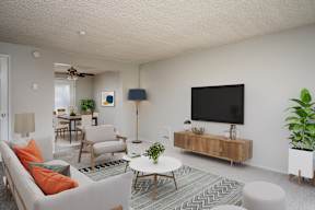 A living room with a white couch, a coffee table, and a television.