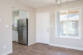 A kitchen with a refrigerator, a door, and a window.
