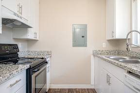 A kitchen with a black stove top oven and white cabinets.