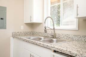 A kitchen with a granite countertop and a stainless steel sink.