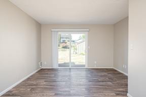 A room with wooden floors and a sliding glass door leading outside.