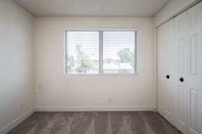 an empty bedroom with a large window and white doors