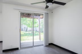 an empty room with sliding glass doors and a ceiling fan