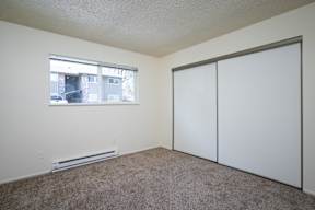 A room with a window, a wall-mounted air conditioner, and a sliding door.
