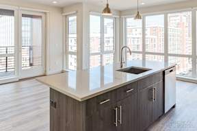 A modern kitchen with a large island and wooden cabinets at The Anthem at Square 10 Apartments, New Haven, 06510
