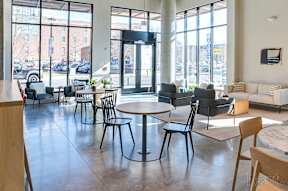 A large room with tables and chairs and a view of the street outside at The Anthem at Square 10 Apartments, Connecticut, 06510