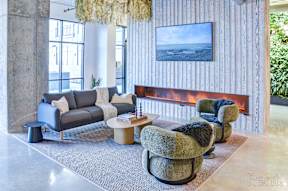 A living room with a grey couch, a green armchair and a fireplace at The Anthem at Square 10 Apartments, New Haven