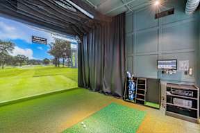 A golf simulator room with a large screen showing a golf course.