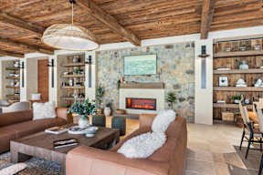 A cozy living room with a stone wall and a fireplace.