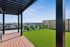A patio with a wooden floor and green chairs.