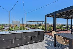 A patio with a bar and chairs overlooking a cityscape.