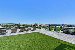 A rooftop patio with green lawn chairs and a view of the city.