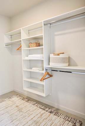 A white closet with a hanger and a basket on the shelf.
