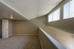 an empty room with a carpeted floor and three windows