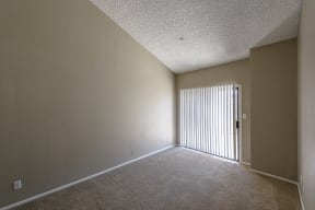 an empty bedroom with a door leading to a balcony