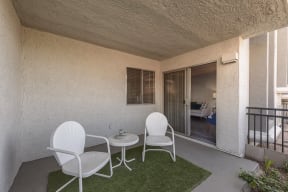 a patio with two white chairs and a small table