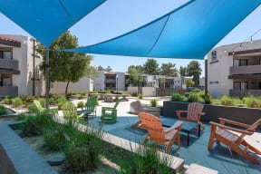 Peoria Apartments- Moxi Apartments-  a seating area with chairs and tables on a sunny day