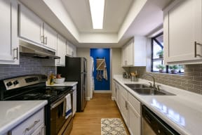Peoria Apartments- Moxi Apartments-  a kitchen with white cabinets and black appliances