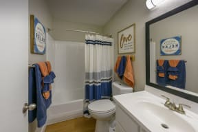 Peoria Apartments- Moxi Apartments-  a bathroom with a white sink and toilet next to a bathtub with a shower curtain and