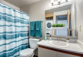 Seattle Apartments-  a bathroom with a toilet, sink, mirror and shower