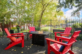 a patio with red chairs and a table and a fire pit