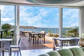 A patio with a table and chairs overlooking a body of water.