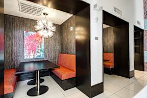 A modern dining area with a black table and orange chairs.