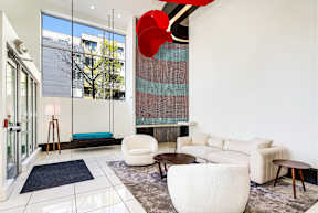 A modern living room with a white sofa and a red sculpture.
