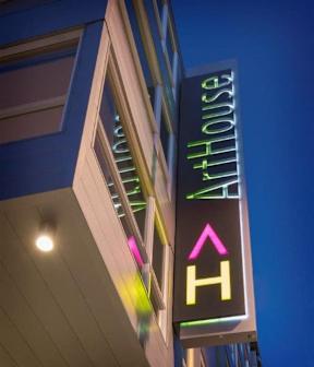 A sign for a place called "Art House" is illuminated in the dark.