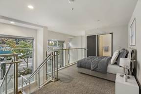 A bedroom with a large bed and a glass railing.