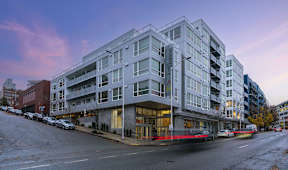 A modern apartment building with cars parked in front.