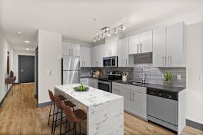 A modern kitchen with a marble island and stainless steel appliances.