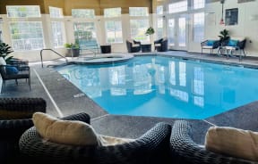 a large indoor pool with chairs and windows in the background